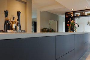 Mat zwart keukeneiland met gebeitste apparatuurwand & haard meubel